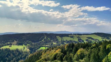 Göz kamaştırıcı ve resimli bir manzara. Yuvarlanan tepeler, yemyeşil ağaçlar ve güzel bulutlu bir gökyüzü.