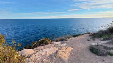 Huzurlu suları ve çarpıcı bir günbatımını gösteren nefes kesici bir sahil manzarası huzur hissi uyandırıyor.