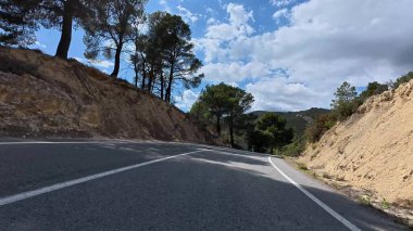 Bereketli ağaçlar ve göz kamaştırıcı manzaralarla çevrili dolambaçlı bir dağ yolu var.