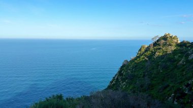 Uçsuz bucaksız okyanusun berrak mavi gökyüzünün altındaki yemyeşil uçurumdan nefes kesici ve çarpıcı manzarası.