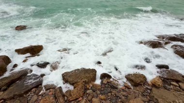 Güzel dalgalar zarif bir şekilde kayalık kıyılara çarpar. Doğanın nefes kesici gücünü ve sükunetini gösterir.