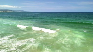 Bu büyüleyici ve çarpıcı deniz manzarası, kumlu sahile çarpan canlı okyanus dalgalarını sergiliyor.