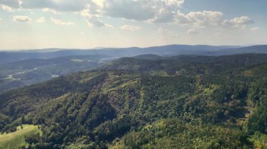 Yeşil dağların ve yuvarlanan tepelerin çarpıcı hava perspektifi, doğanın sükunetini yakalıyor..