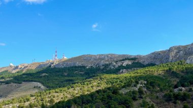 Görkemli dağların ve yemyeşil yeşilliğin göz kamaştırıcı manzarası berrak mavi gökyüzünün altında, doğanın güzelliğini ön plana çıkarıyor.