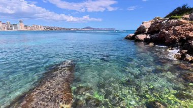 Nefes kesici bir sahil manzarası göz kamaştırıcı berrak suları sergiliyor. Resmedilmeye değer bir şehrin siluetinin yanında.