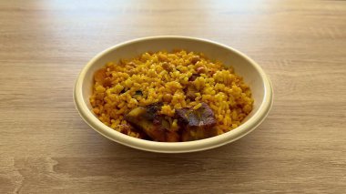 Lezzetli sarı pirinç, taze sebze ve sulu etle dolu canlı ve renkli bir kase.