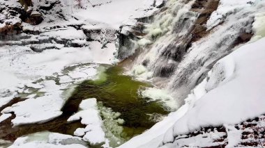 Göz kamaştırıcı bir kış sahnesi kar ve buzla çevrili görkemli çağlayan şelaleyi sergiliyor.
