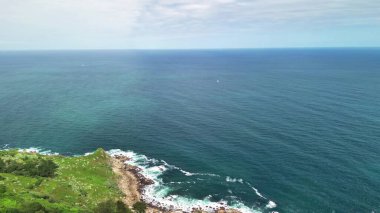 Resimli sahil şeridi boyunca kayalıkların ve canlı yeşilliklerin nefes kesici hava manzarası