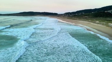 Kesinlikle nefes kesici bir hava manzarası alacakaranlıkta sakin bir plajda sallanan yumuşak dalgaları yakalar.