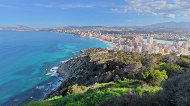 Nefes kesici bir manzara, berrak mavi gökyüzünün altında, güzel deniz kıyısında canlı bir kıyı şehrini gösteriyor.
