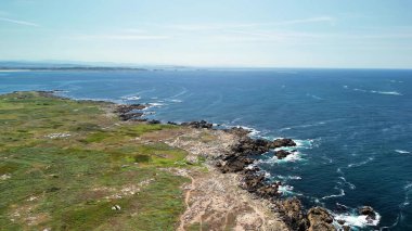 Nefes kesici bir hava manzarası, engebeli bir kıyı şeridini, berrak mavi gökyüzünün altında engin okyanusla çarpışıyor.