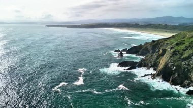 Muhteşem sahil şeridinin nefes kesici hava manzarasını deneyin, dalgalar görkemli kayalıklara çarpıyor.