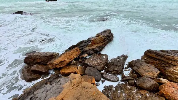 Büyüleyici manzara dalgaları çarpıcı bir şekilde engebeli kayaların üzerine çarpıyor çarpıcı güzellikte bir sahil şeridi boyunca.