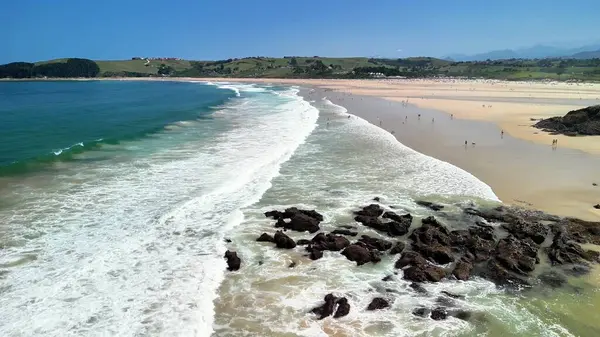 Dalgaları ve güneşten hoşlanan insanları gösteren canlı, renkli bir plajın kesinlikle nefes kesici bir görüntüsü.
