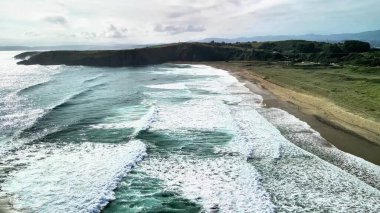 Hava görüntüleri, sakin ve dingin bir sahile çarpan dalgaları güzel bir şekilde yakalıyor.