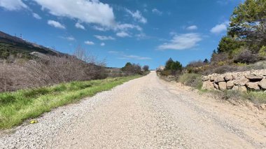 Güzel ve pitoresk bir çakıl yolu yavaşça kıvrılıyor canlı yemyeşil ve parlak mavi gökyüzünde.