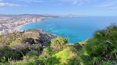 Güneşli, mavi gökyüzünün altında nefes kesici kıyı şeridi ve kristal berrak suların nefes kesici manzarasını tecrübe edin.