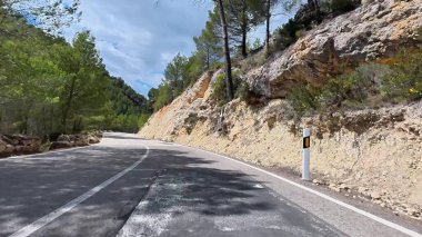 Güzel ve büyüleyici bir yol yemyeşil ağaçlar ve çarpıcı kayalık yamaçlarla çevrili.