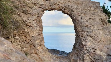Uçsuz bucaksız okyanusun şaşırtıcı güzellikteki manzarası berrak gökyüzünün altındaki doğal bir kaya kemeri tarafından mükemmel çerçevelenmiştir.