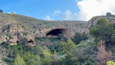 Göz kamaştırıcı bir mağaranın nefes kesici görüntüsü parlak mavi gökyüzü tarafından aydınlatılan canlı yeşil bir arazide gizlenmiş.