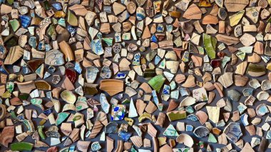 Kırık çömlek parçalarının canlı bir görüntüsü, sanatsal düzende renkler ve dokular sergiliyor..