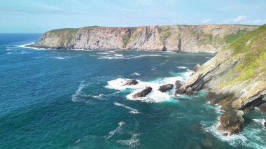 Nefes kesen sahil kayalıkları muhteşem bir şekilde aşağılarındaki büyüleyici masmavi sulara ve kayalık kıyılara bakıyor.