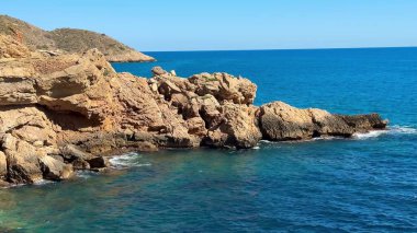 Güzel, sakin bir sahil manzarası göz kamaştırıcı mavi okyanus suları ve berrak bir gökyüzünün altındaki engebeli kıyı şeritleri