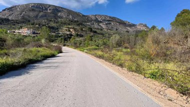 Resimli ve büyüleyici bir yol, verimli, canlı yeşillikler ve görkemli dağların arasında güzel bir şekilde dönüyor.
