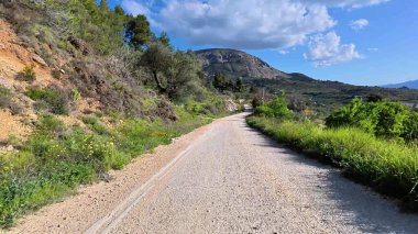 Huzurlu ve güzel çakıllı bir yol çarpıcı yeşil manzaralar ve görkemli dağlar arasında zarif bir şekilde kıvrılıyor.