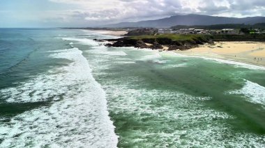 Nefes kesici bir hava manzarası, çarpıcı kıyı manzarasının ortasında kıyı şeridine çarpan yumuşak dalgaları yakalar.