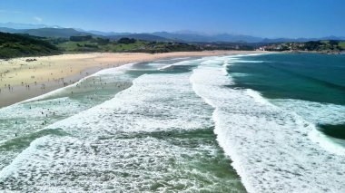 Sörfçülerle nefes kesen sahneler, berrak gökyüzü ve havadan çekilen canlı dalgalar.