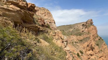 Nefes kesen manzara, aşağıdaki sakin mavi denizi görkemli bir şekilde gören engebeli sahil kayalıklarını gösteriyor.