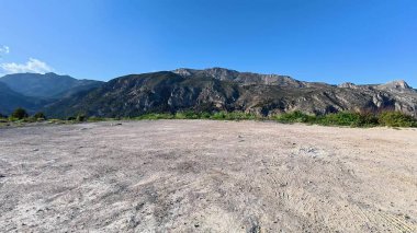 Nefes kesici ve çarpıcı bir manzara. Yüksek dağlar ve berrak mavi gökyüzünün altında canlı bir yeşillik.