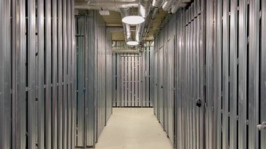 Çağdaş bir depolama tesisi koridorunda parlak metal bölümler ve parlak, etkili aydınlatma çözümleri sergileniyor