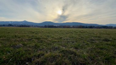 Heybetli dağların, açık otlakların ve sakin bir alacakaranlık gökyüzünün yer aldığı şaşırtıcı derecede huzurlu bir manzara.