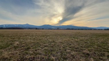 Uçsuz bucaksız bir açık arazinin nefes kesici sakin görüntüsü titreyen bir gökyüzünün altındaki yüksek dağlara doğru nazikçe ilerliyor.