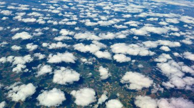 Çarpıcı bir hava perspektifi, güzel, pofuduk bulutları yakalar ve verimli kırsal bölgede zarafetle sürüklenir.