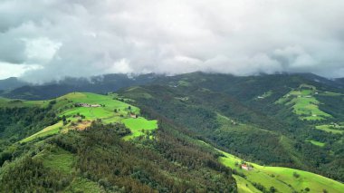 Nefes kesici bir manzara, geniş bulutlu gökyüzü altında yemyeşil tepeler sergiliyor, doğa severler için ideal.