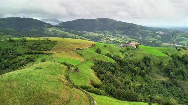 Geniş yeşil tepelerin ve bulutlu gökyüzünün altında uzanan yemyeşil vadilerin nefes kesici güzelliğini keşfedin.