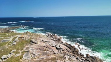 Engebeli kayaları ve dalgalı okyanus dalgalarını güzellikle ön plana çıkaran çarpıcı deniz manzaraları.
