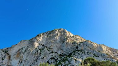 Berrak mavi gökyüzüne karşı kurulmuş kayalık bir dağ manzarasının nefes kesici ve olağanüstü manzarasının tadını çıkarın.