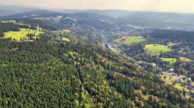 Bu çarpıcı hava perspektifi aşağıdaki sakin vadilerin yanında yemyeşil ormanları güzel bir şekilde sergiliyor.
