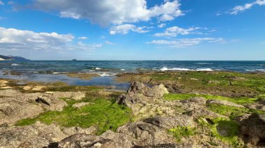 Kayalık kıyı şeridinin, canlı yeşilliğin ve berrak mavi gökyüzünün altındaki sakin suların tadını çıkar.