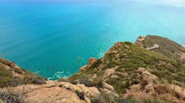 Kayalık bir uçurumdan gelen turkuaz denizin çarpıcı manzarası nefes kesici güzelliği ve cazibesini sergiliyor.