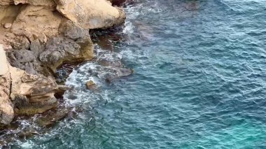 Engebeli bir kayalık kıyı şeridi sakin okyanus sularıyla buluşur, şaşırtıcı güzellikler ve cazibeler sergiler.