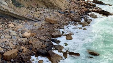 Dalgaların sahile çarptığı nefes kesen kayalık bir kıyı manzarası.