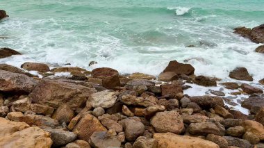 Dinamik dalgalar, sakin ve sakin bir sahil çevresi boyunca kaya ve kayalarla sürekli etkileşim halindedir.