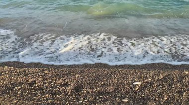 Okyanus dalgalarının dingin ve çarpıcı güzelliğini yakalayın. Güzel, çakıl taşlı bir kıyıda yavaşça yıkanırken.