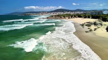 Nefes kesici ve çarpıcı kıyı manzarası, temiz mavi gökyüzünün altındaki el değmemiş dalgaları ve kumlu kıyıları gösteriyor.