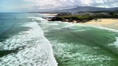 Nefes kesici bir hava manzarası, çarpıcı kıyı manzarasının ortasında kıyı şeridine çarpan yumuşak dalgaları yakalar.
